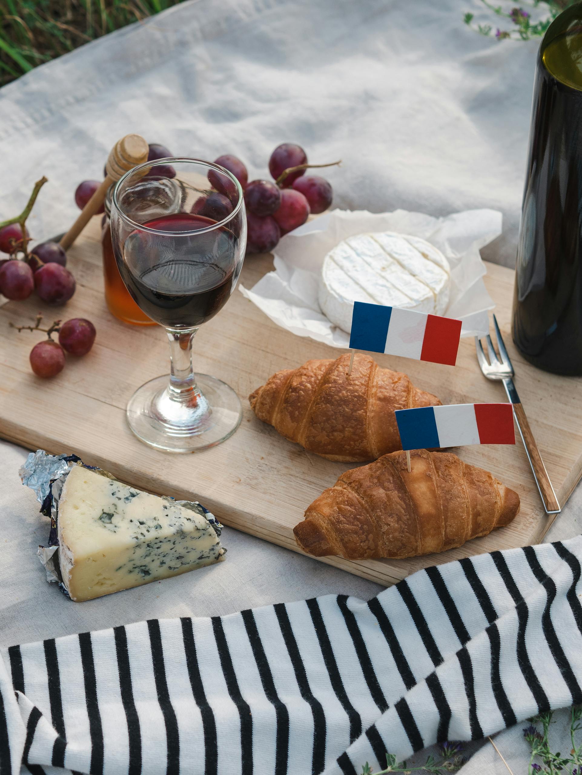 A delightful French picnic featuring croissants, cheese, and wine, styled with French flags.